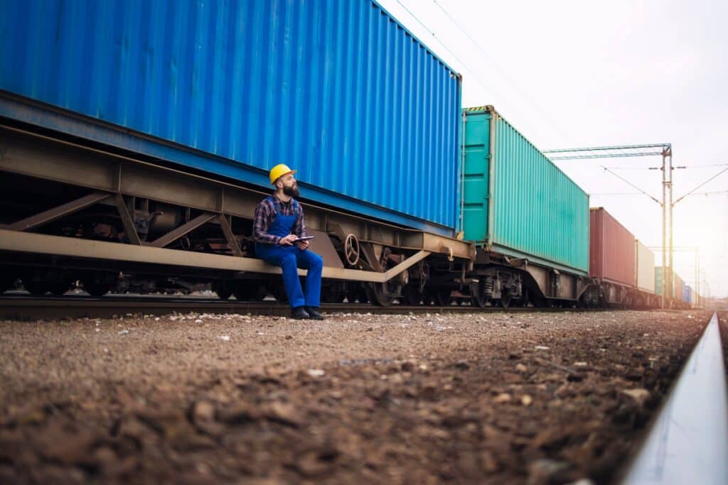 A man checking the containers on the cargo train.