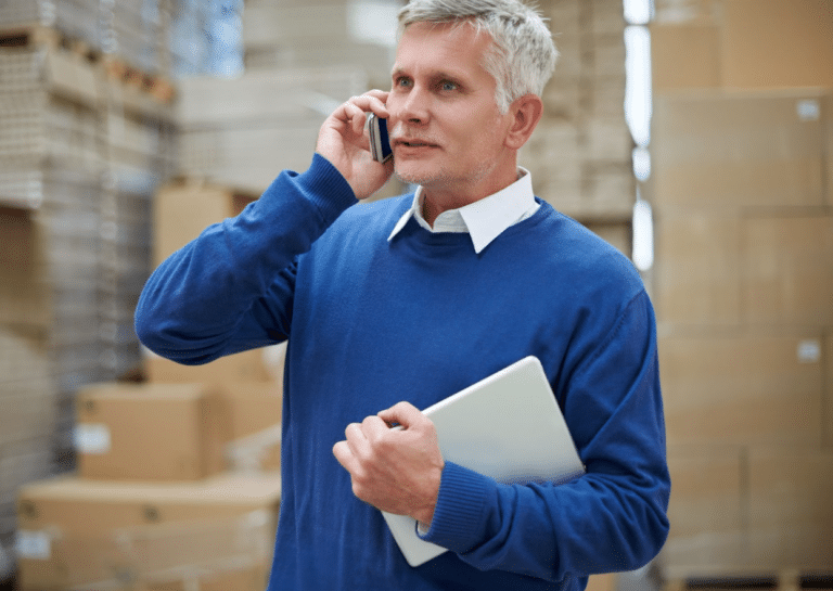 A man talking to a freight broker on a phone.